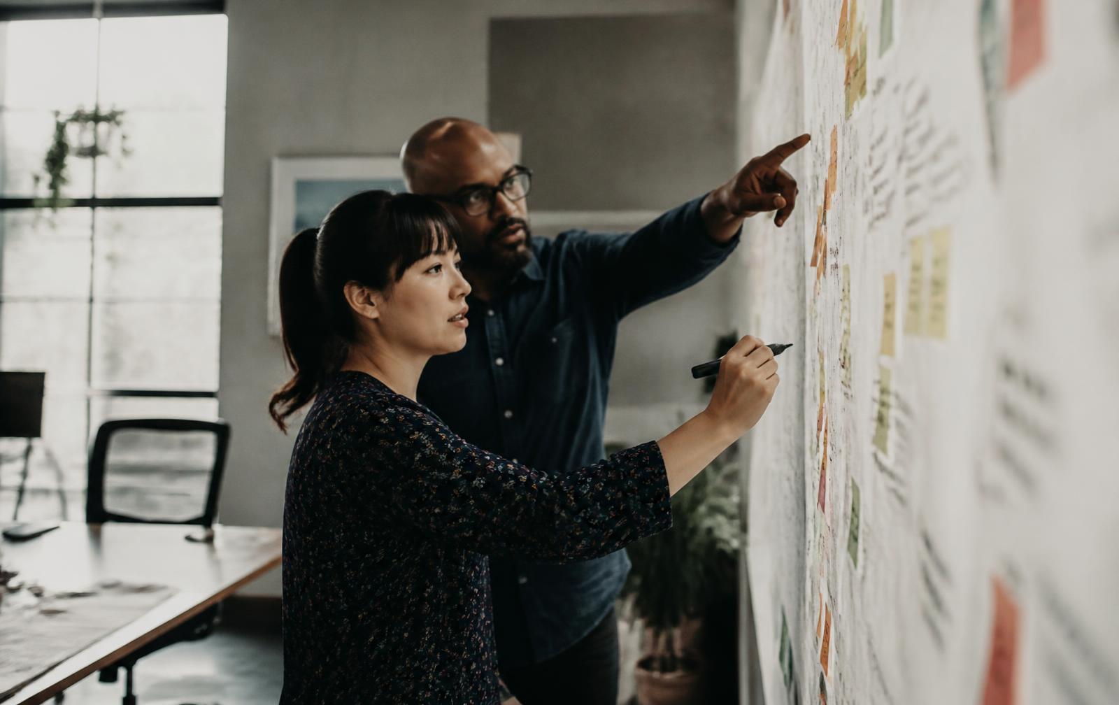 Two colleagues mapping a process across a wall of notes